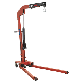 The Sealey Folding Engine Crane 1 Tonne - SPC1000 is a red hydraulic hoist with black accents, equipped with a heavy-duty forged lifting hook at the end of an adjustable arm and mounted on wheels for mobility. Ideal for professional workshop use.