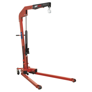 The Sealey Folding Engine Crane 1 Tonne - SPC1000 is a red hydraulic hoist with black accents, equipped with a heavy-duty forged lifting hook at the end of an adjustable arm and mounted on wheels for mobility. Ideal for professional workshop use.