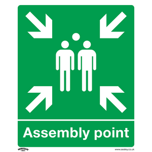 The Sealey Safe Conditions Safety Sign - Assembly Point (SS37P10), crafted from rigid plastic, features a green background with white figures and four inward-pointing arrows. The text "Assembly point" is written underneath, making it ideal for commercial environments such as offices or workshops. Available in a pack of 10.