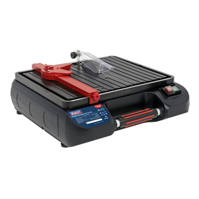 The Tile Cutter Ø115mm Portable - TC115 from Sealey is a lightweight and portable wet tile cutter that features an electric motor, a red adjustable arm, and a black grooved cutting surface. It is equipped with side control buttons and has a clear safety guard near the diamond cutting blade for precise and safe operation.