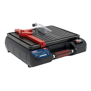 The Tile Cutter Ø115mm Portable - TC115 from Sealey is a lightweight and portable wet tile cutter that features an electric motor, a red adjustable arm, and a black grooved cutting surface. It is equipped with side control buttons and has a clear safety guard near the diamond cutting blade for precise and safe operation.