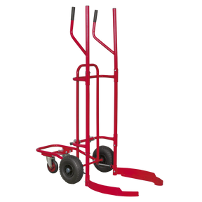 The Sealey Tyre Trolley - 150kg Capacity - TH003 is a red hand truck with tall vertical handles, curved supports, and two large pneumatic tyres designed for moving cylindrical objects, featuring a sturdy tubular steel construction.