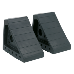 The Sealey Rubber Wheel Chocks - Pair - WC01 are two black rubber chocks designed to prevent vehicle movement. They feature a grooved surface and side holes for securing, making them perfect for ensuring vehicle incline safety.