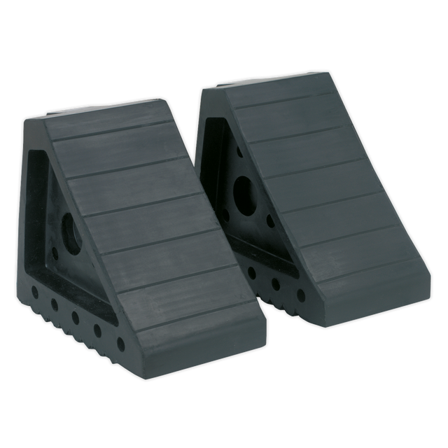 The Sealey Rubber Wheel Chocks - Pair - WC01 are two black rubber chocks designed to prevent vehicle movement. They feature a grooved surface and side holes for securing, making them perfect for ensuring vehicle incline safety.