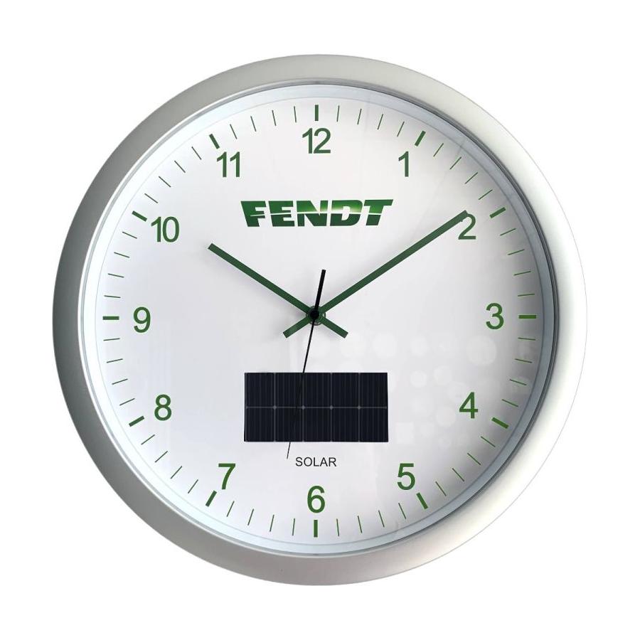 A sleek, modern round solar wall clock featuring a white face with green numerals and hands, branded "AGCO" at the top. The Fendt Solar Wall Clock X991023035000 showcases precise quartz clockwork and includes a small solar panel below the center, effortlessly combining efficiency with style.