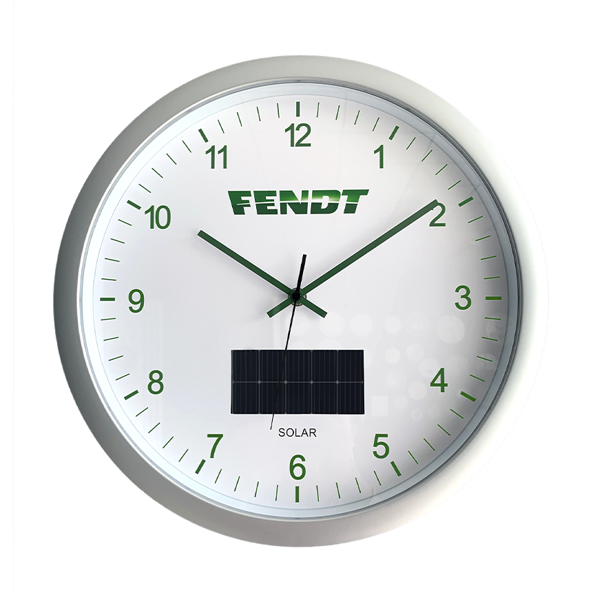 The Fendt - Solar wall clock - X991023035000 by AGCO features a round design with the "FENDT" logo and a modern aesthetic. It incorporates a solar panel positioned below the center, with green clock hands and numerals set against a white background. The Quartz clockwork ensures precise timekeeping.