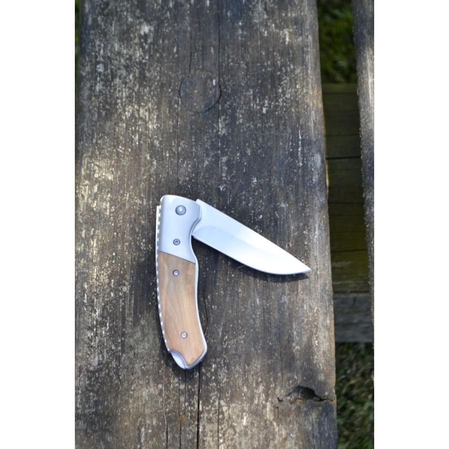 The Massey Ferguson Folding Pocket Blade (model X993562301000) by AGCO, featuring a durable wooden handle and a partially open stainless steel blade with a reliable locking system, rests on a weathered wooden surface.