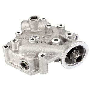 A metallic automotive engine part with multiple bolt holes and threaded connectors, similar to the AGCO Oil Filter Head - F824200310470 found in Valtra models.