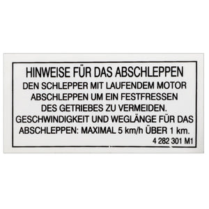 The AGCO | Decal - 4282301M1, a German sign from AGCO providing towing instructions, warns to keep the engine running to avoid gear seizure and specifies a towing speed limit of 5 km/h over a distance of up to 1 km. The decal features factory-engineered stickers for enhanced visibility and durability.