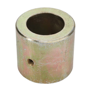 The AGCO | BUSH - D49073300 is a cylindrical metal bushing featuring a central hole and a smaller side hole for fastening. The surface shows signs of wear with a slightly tarnished finish. There is no current product description information available from the manufacturer.