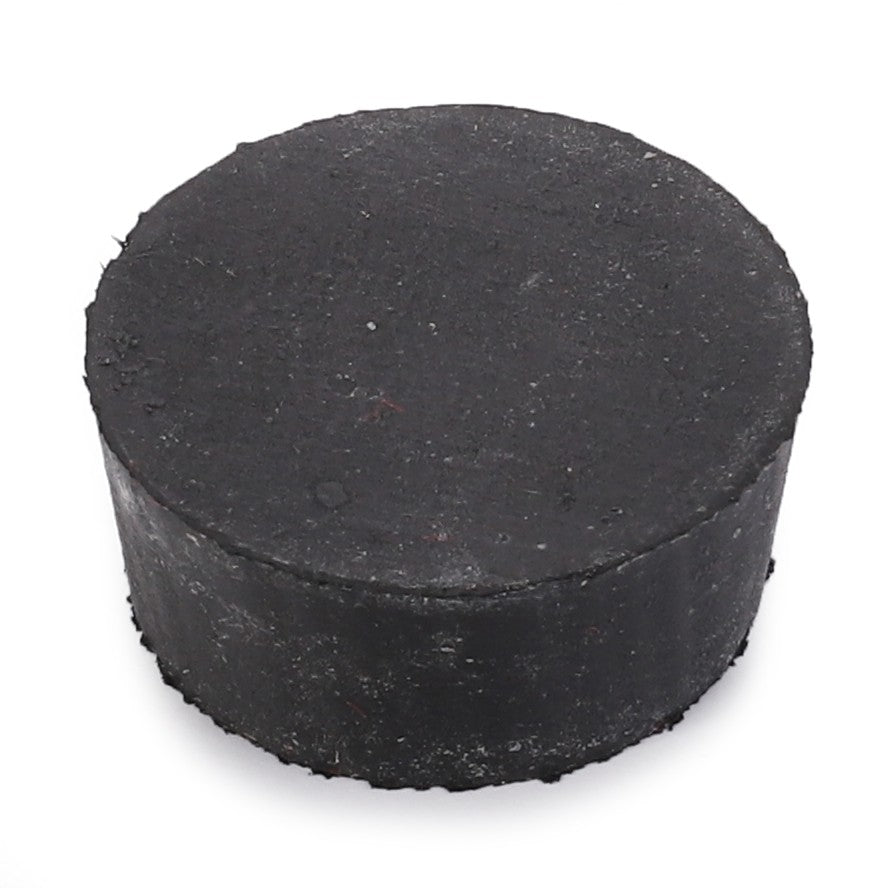 A black cylindrical object, resembling a hockey puck, positioned against a white background—its design simplicity reminiscent of the streamlined aesthetics found in AGCO models like the Plug - 180982M1.