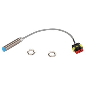 The AGCO Inductive Sensor - Acw0926390 is a cylindrical metal sensor featuring a blue tip. It is connected by a gray wire to a black and red connector, and comes with two hex nuts placed beside it.