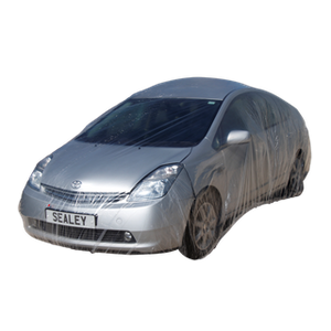 A silver car wrapped in the Sealey Temporary Universal Car Cover Large (TDCCL) with a license plate reading "SEALEY 1"—ideal for bodyshops, this disposable full car cover protects the vehicle from scratches.