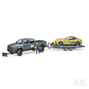 A Bruder RAM 2500 Power Wagon is towing a flatbed trailer with a Bruder Roadster Racing Team's yellow race car, and a miniature figure stands beside the truck.