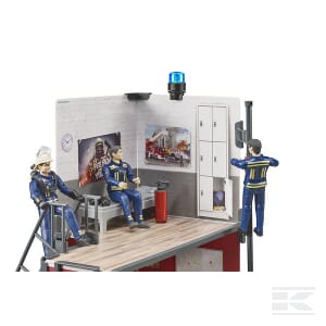 Three firefighter figures in a 1:16 scale diorama depicting a fire station interior feature one figure climbing a pole while the other two are seated. The scene includes lockers, posters, and firefighting equipment, all enhanced by the realistic touch of Bruder's Accessories: Rotating beacon light - U02807.