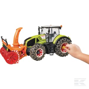 A child's hand interacts with a green and orange Claas Axion 950 toy tractor by Bruder, model U03017, featuring large tires and a front snow blower attachment, closely resembling real agricultural machinery.