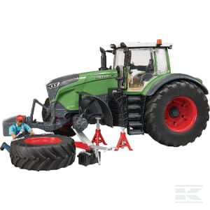 A Farming Parts Fendt 1050 Vario + mechanic - U04041 tractor with large red wheels is being repaired by a miniature plastic mechanic figure. The mechanic is working on a detached wheel placed on the ground, using a toolkit and a jack stand.