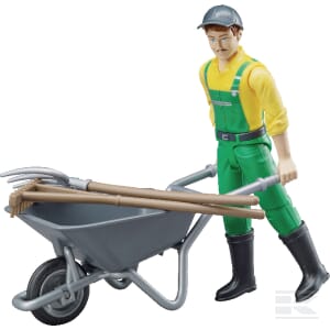 The Bruder Figure set farmer with accessories - U62610 features a toy figurine of a farmer in a yellow shirt and green overalls, standing next to a gray scale 1:16 wheelbarrow filled with gardening tools.