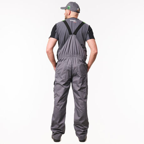 A man viewed from behind wearing a pair of dark gray waterproof overalls with black suspenders, a black t-shirt, and a gray cap, against a plain white background.