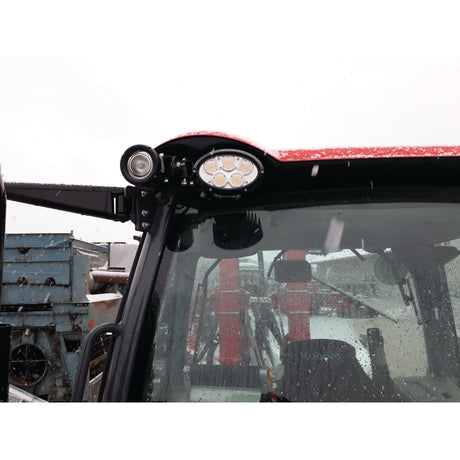 Close-up of a vehicle's front light and windshield with a red roof, seen in a snowy outdoor environment. The Sparex LED Work Light (Cree High Power), delivering an extraordinary 10000 lumens raw and featuring an IP68 rating, ensures exceptional visibility even in harsh weather conditions.