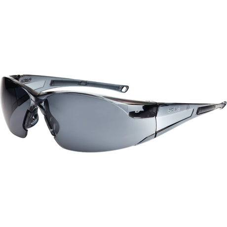 The Sparex Safety Glasses, featuring smoke grey lenses and translucent gray frames, offer UV protection and lightweight comfort in a sleek, rimless design.