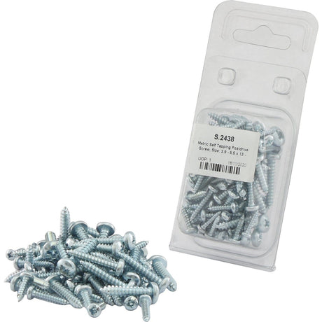 A pile of metal screws, including the Metric Self Tapping Pozidrive Screws (2.9 - 5.5x13 - 25mm, DIN 7981B) from Sparex Part No.S.2438, is placed next to a clear plastic packaging containing more of these Sparex brand screws. The packaging has a label with text and a barcode.