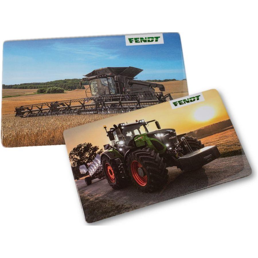 The Fendt Snack Board Set of 2 (X991021051000) by AGCO features vibrant images of Fendt agricultural machinery, with one showing a combine harvester in a field and the other a tractor on a road at sunset. These BPA-free placemats are dishwasher-safe for easy cleaning.