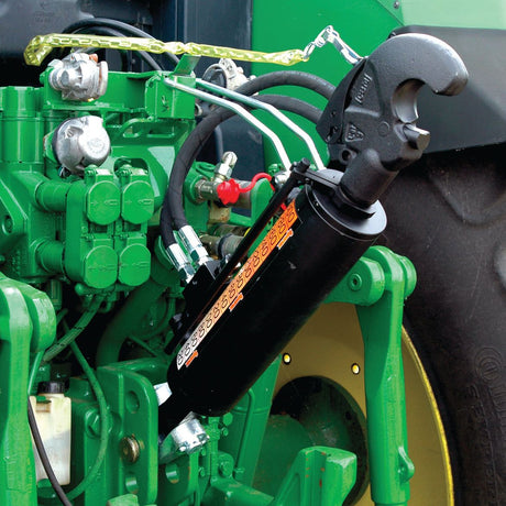 Close-up of a Sparex Hydraulic Top Link (Cat.28mm/3) Knuckle and Q.R CBM Hook, connected to a green agricultural machine, showcasing various pipes, valves, and components. This versatile tractor implement features a robust 90mm cylinder bore for efficient performance in the field with a minimum length of 650mm (Sparex Part No. S.331203).