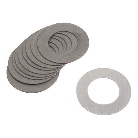 Several round metal washers are arranged in a stack, with one Sparex Shim (Sparex Part No.S.40147) placed separately beside the stack, all ready for use with a Massey Ferguson tractor.