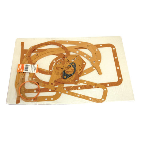 A flat set of variously shaped brown gaskets and one orange O-ring, arranged on a white background. The Sparex Bottom Gasket Set - 4 Cyl. (Sparex Part No.S.40602) is ideal for ensuring a reliable seal for your 4 Cyl Massey Ferguson machinery.