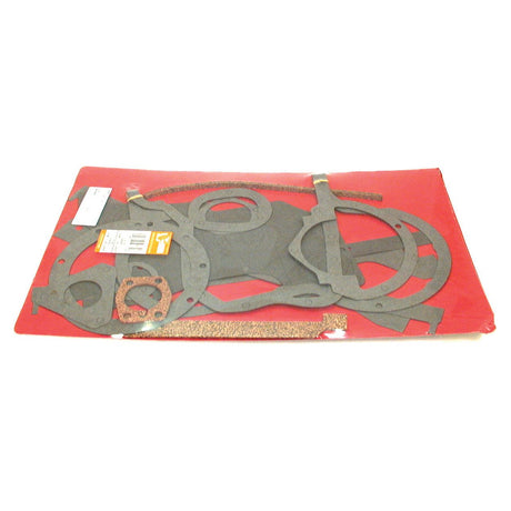 A Sparex Bottom Gasket Set - 4 Cyl. (A4.107, A4.192, AD3.152, AD4.203, AT4.236) | Sparex Part No.S.40609 for Perkins Engine, featuring variously shaped gaskets arranged on a red background and packaged in a flat plastic wrap.