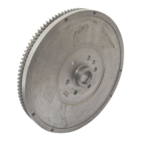 This is a Flywheel Assembly 13'' (Sparex Part No. S.43788) by Sparex, featuring a circular metal design with a central hole and multiple smaller holes around it. The outer edge has evenly spaced teeth, and it shows signs of use with slight tarnishing, reminiscent of an old workshop Massey Ferguson part.