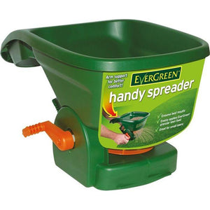 A green JMCE Handy Spreader - 381970 with a handle and an orange dial, ideal for smaller lawns, designed for even distribution of grass seed or granular lawn care products. The label highlights features such as arm support and spreading efficiency.