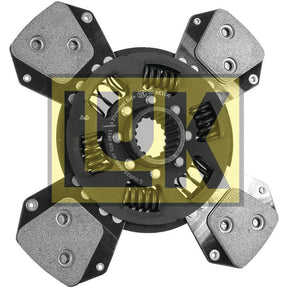 Close-up image of a metal clutch plate with four pads and springs, marked with text in Cyrillic script and visible part numbers. The background features a semi-transparent yellow logo overlay. The detailed shot reveals the spline design, enhancing the functionality of this Sparex component - Clutch Plate (S.156483).