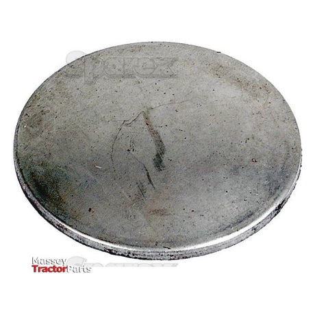 A round, flat metal disk with a plain surface and slightly worn appearance, partially showing the words "Massey Tractor Parts" on the lower left, this Core Plug - 1 1/2'' (Dished Type - Mild Steel) from Sparex (Part No. S.19175) appears to be made of mild steel.