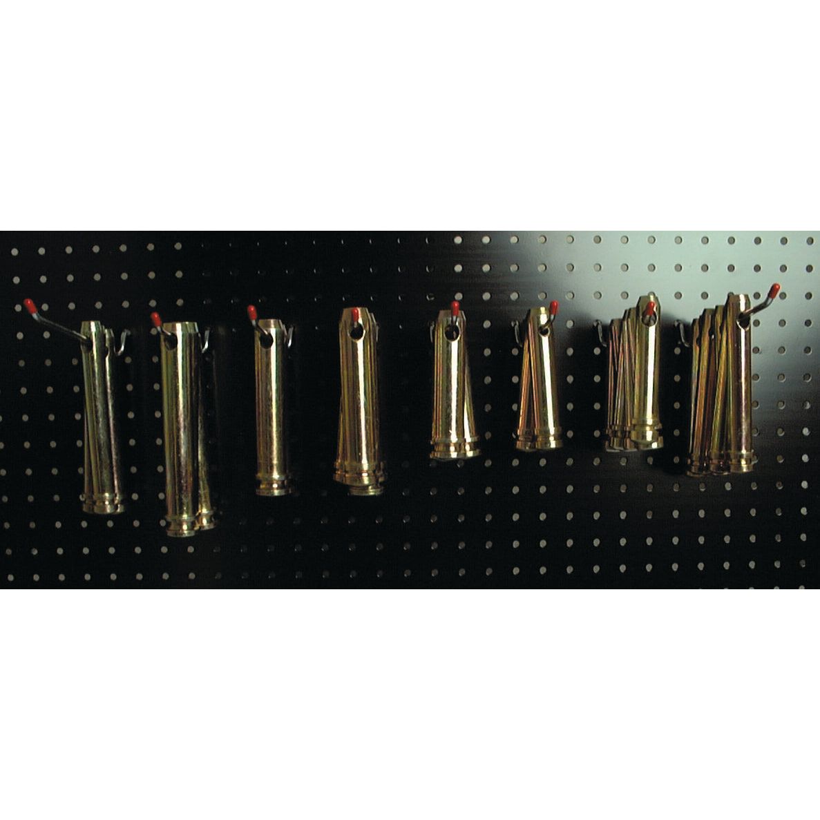 A row of brass fire hose nozzles with red tips, reminiscent of the Sparex Dispenser Kit - Top Link Pins - Cat. 1/2 (Sparex Part No.S.2304), hanging on hooks on a perforated black metal board.