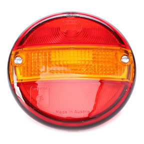 The AGCO Fendt - Hella Glass Lens - F716900020040 is a round tail light featuring red and amber sections, two screws, and embossed text indicating "Made in Austria." It is equipped with a high-grade glass lens for enhanced durability, making it an ideal choice for Fendt models to ensure quality and authenticity.