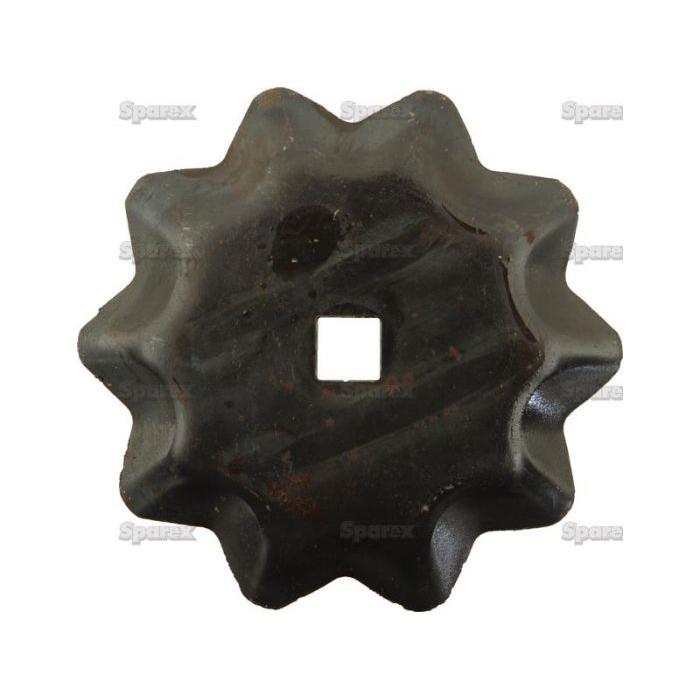 A rusted, dark-colored, jagged-edged metal piece resembling a Sparex Feeder Wagon Knife Ø97mm, Sparex Part No. S.106476, with a square hole in the center.