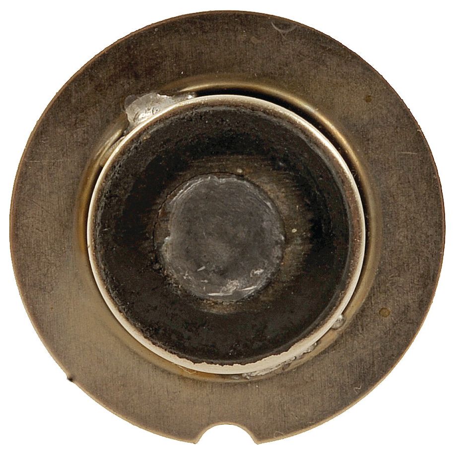 A close-up view of a metallic circular object with a central darkened area, possibly showing signs of wear or corrosion, resembles the base of a Sparex Light Bulb (Filament) 12V, 36W, P22s (Sparex Part No.S.28397).