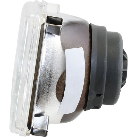Side view of a rectangular fog light bulb with a metallic housing and a black rubber gasket. A white sticker is attached to the side. The lens is clear, and the overall component appears new. This Sparex Head Light, (Halogen), RH & LH, RH Dip, 12V - S.31920 ensures optimal visibility in foggy conditions.