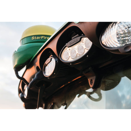 Close-up of a tractor's lights and GPS receiver. The image shows the brand "StarFire" on the GPS unit atop the machine, manufactured with precision, and multiple Sparex LED Work Lights (Cree High Power, 7000 Lumens Raw) mounted near the windshield, suitable for nighttime operations.
