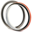 Two circular metal seals from Sparex, one featuring an orange outer edge and the other with a gray edge. Both include inner black rubber rings and are designed for sealing applications, making them ideal for Metric Rotary Shaft Seals in Ford / New Holland machinery. The specific product details are Metric Rotary Shaft Seal, 125 x 150.5 x 14.3mm | Sparex Part No.S.59505.