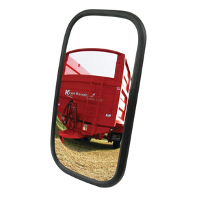 A close-up of the Sparex Mirror Head - Rectangular, Convex, 240 x 130mm (S.6221) with a black frame, reflecting a red agricultural trailer on a grassy field. The convex mirror captures every detail vividly.