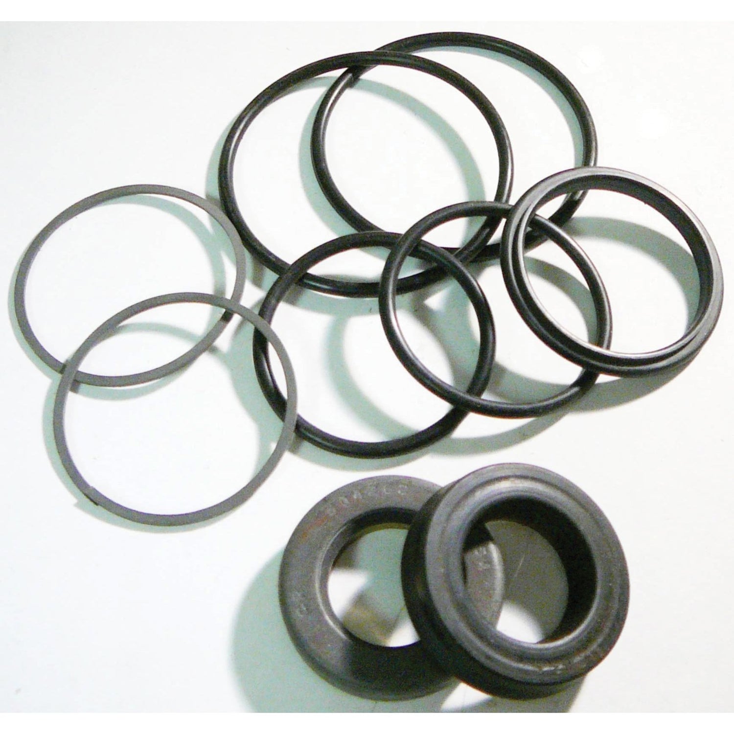 This essential Seal Kit, perfect for maintaining your Ford New Holland power steering cylinder, includes a collection of various-sized black rubber O-rings and two black rubber grommets on a white surface. It is the Power Steering Cylinder Seal Kit by Sparex (Part No. S.61899).