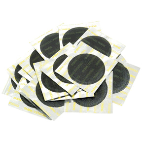 A pile of black circular REPAIR PATCH - TUBE - 55MM (Sparex Part No.S.19801) adhesive patches from Sparex sits on rectangular white and yellow backing paper.