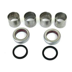 The Spindle Repair Kit (Sparex Part No.S.65111) by Sparex features four silver cylindrical metal bushings, two round metal bearings with visible red interiors, and two black rubber O-rings arranged on a white background, ideal for Ford / New Holland machinery.