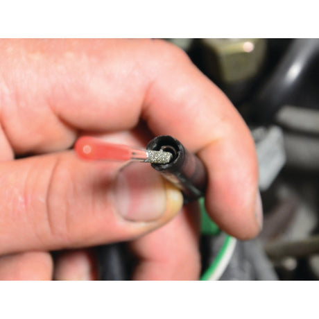 A hand holding a black wire near the end, exposing frayed silver strands inside, suggests it may need attention from Sparex Super hard Diamond-Coated Round Micro Files - S.151751 for precision fixes.