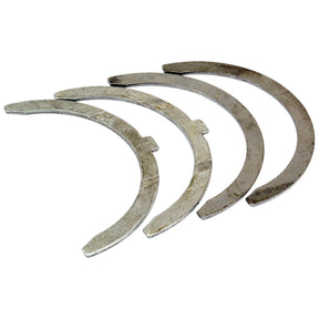 Four crescent-shaped metal pieces arranged in a partially overlapping pattern, each with a notch on one side, form the essential components of the Sparex Thrust Bearings Set (Sparex Part No.S.52623).